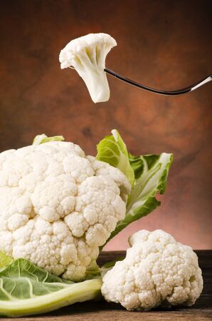 a fork with a part of a raw cauliflower in the foregroundの写真素材