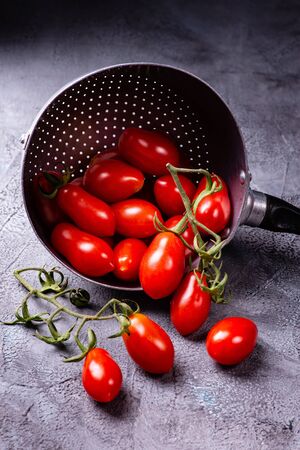fresh and ripe tomatoes in the old colander on a rustic gray backgroundの写真素材