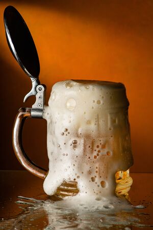 fresh and frothy beer overflowing from the glass mugの写真素材