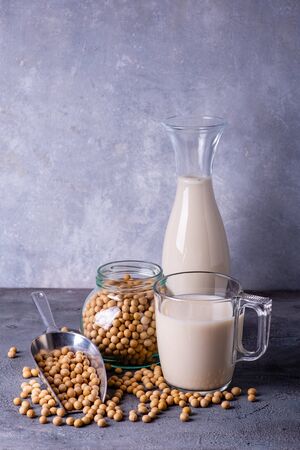On the rustic gray background, a glass with soy milk and yellow soy beans in the clear glass bowlの写真素材