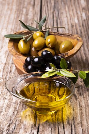 selective focus. On the rustic wooden table, bowls with olives, olive branch and extra virgin olive oilの写真素材