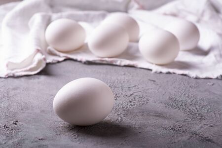 in the kitchen on the gray textured background, in the foreground, fresh white eggs ready for the...