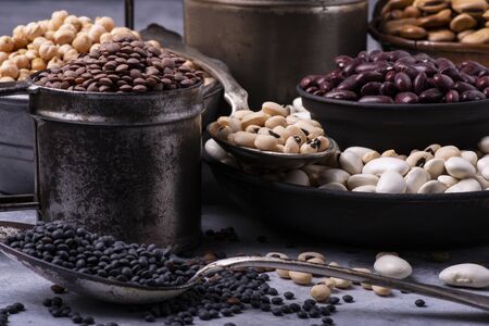 in different rustic metal bowls, on a gray textured background, variety of raw and colorful dry legumes rich in proteinの写真素材