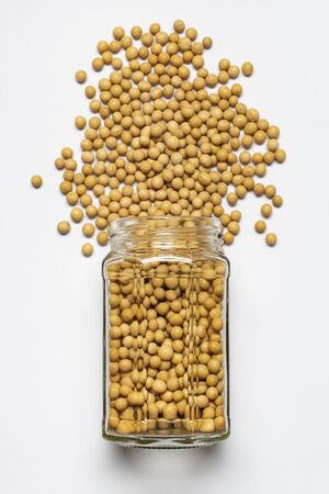 glass jar with yellow soybean in the foreground, top view, isolated from the white backgroundの写真素材
