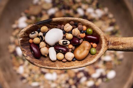 top view, selective focus, in a rustic wooden spoon variety of raw and colorful dried legumes rich in proteinの写真素材