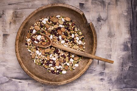 top view, in a rustic wooden plate variety of raw and colorful dry legumes rich in proteinの写真素材