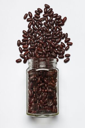 glass jar with red beans in the foreground, top view, isolated from the white backgroundの写真素材