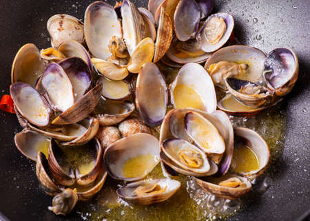 In the foreground, a pan scented with clams sauteed with garlic, oil, cayenne pepper and mixed with white wineの写真素材