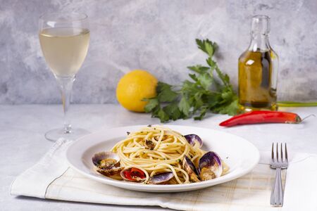 in the foreground, on a textured gray background, fragrant plate of spaghetti with clamsの写真素材