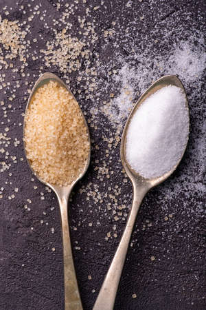 on a slate stone, in the foreground, spoons with raw and white refined cane sugar.の写真素材