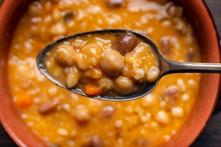 in the foreground, with a view from above, a tasty organic and vegetarian soup with legumes, vegetables and cereals ready to be enjoyedの写真素材