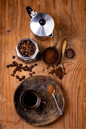 on the rustic wooden background, with top view, roasted coffee beans, an Italian coffee pot and a cup of black coffeeの写真素材