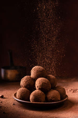 Tasty dark chocolate truffles with cocoa dusting on a brown backgroundの写真素材