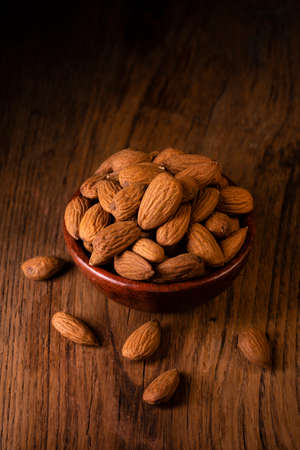 In the foreground, a group of shelled almonds in an earthenware bowl.の写真素材