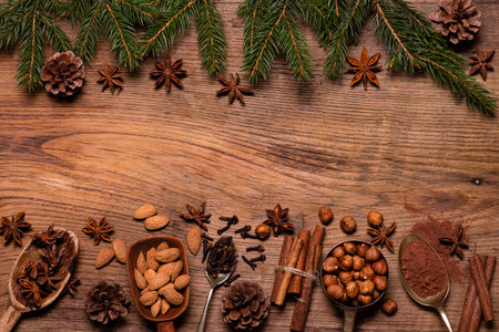 Top view, on a textured wooden background, pine branches with pine cones, various spices and dried fruits. Blank space for your text. Christmas scene.の写真素材