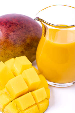 In the foreground, a slice of chopped mango and a fresh mango smoothie.の写真素材