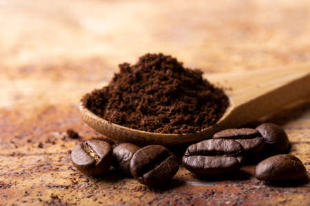 some coffee beans in the foreground with selective focus, in the background coffee powderの写真素材