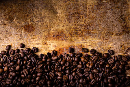 In the foreground, from above, on the textured brown rustic background, roasted coffee beans. Blank space for your textの写真素材