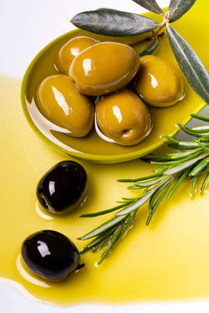 in the foreground, in a green ladle, there are olives with extra virgin olive oil flavored with rosemaryの写真素材