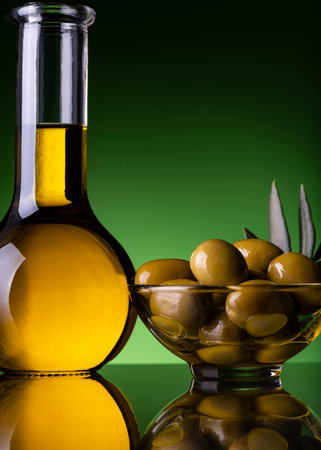 in the foreground a glass cruet with Italian extra virgin olive oil. Side bowl with olives. still lifeの写真素材