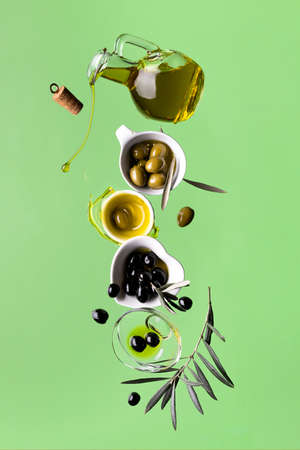 extra virgin olive oil and olives, composition in balance, still life in motion. green backgroundの写真素材