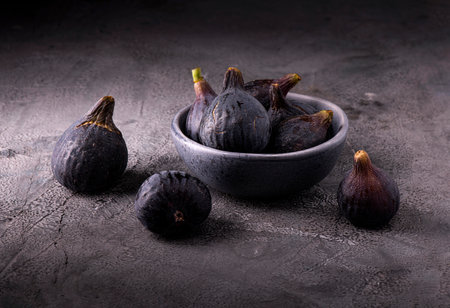 Some ripe figs in a bowl on a textured gray backgroundの写真素材