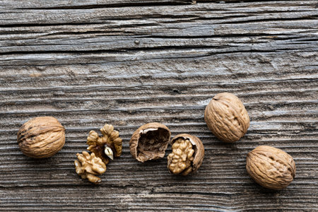 top view, on an old wooden board, in the foreground, some walnuts with and without shell. Copy...