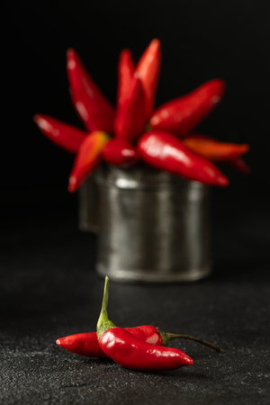 Spicy red chillies in an old metal measuring container on a black background.の写真素材