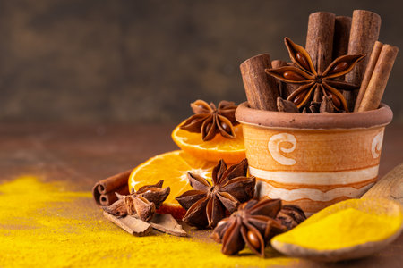 In the foreground various spices and orange slices. In a terracotta jar some cinnamon sticks and a star anise star. Still lifeの写真素材