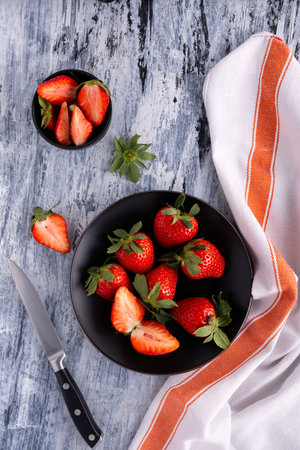 top view, on the textured background, a bowl and a black plate with delicious red strawberries.の写真素材