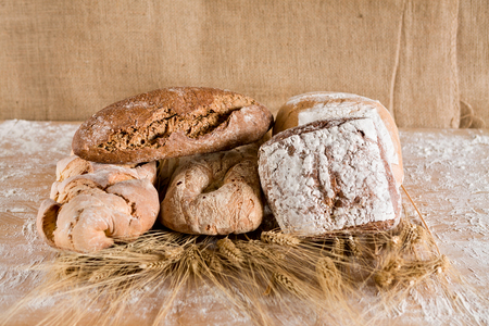 Several kind of loaves with ears of wheat and jute backgroundの写真素材