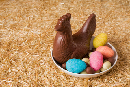 Easter chocolate chicken and eggs in a plate over the straw