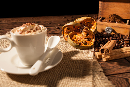 Close-up of coffee cup, dried orange fruit and cinnamon sticks over a wooden backgroundの写真素材