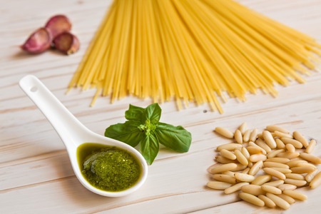 Closeup of pesto genovese sauce and linguine pasta, pine nuts and garlic on a tableの写真素材