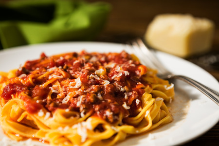 Closeup of tagliatelle pasta with bolognese ragu over a rustic tableの写真素材