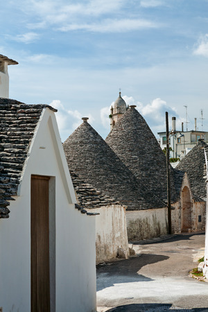 Typical street with Trulli houses under a blue sky in Alberobello, Puglia, Italyの写真素材