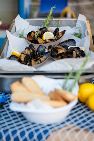 Roasted mussels on a baking pan with lemon and rosemary ready to be eatenの写真素材