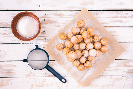 Castagnole, typical Italian carnival sweet with powdered sugar and sieve seen from aboveの写真素材