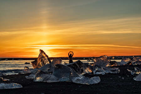 Dancing girl in diamond beach in Vatnajokull National Park at sunset, Icelandの写真素材