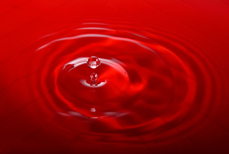 Splashing water droplets on red background.の写真素材