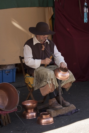 ALCALA DE HENARES, MADRID, SPAIN - OCTOBER 12: man making copper utensils in medieval market held on October 12, 2009 in Alcala de Henares, Madrid, Spainのeditorial素材