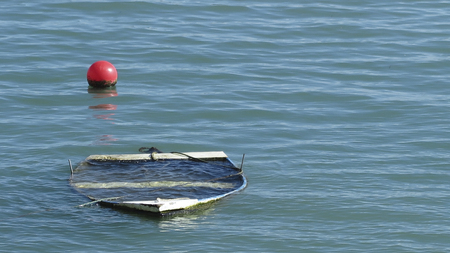 horizontal view of a small wooden boat sunken in the sea