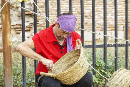ALCALA DE HENARES,  SPAIN - OCTOBER 12,2018: craftsman making wicker baskets during the celebration of a medieval market in the city of alcala de henaresのeditorial素材
