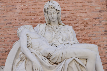 foreground detail of a replica of Miguel Angel famous sculpture the Pieta at Adolfo Suarez park of Torrejon de Ardoz, madrid, spain with wall of bricks as backgroundのeditorial素材