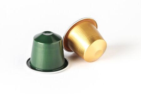 horizontal view of two gold and green color espresso coffee capsules isolated on white backgroundの写真素材