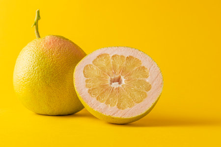 horizontal view in foreground of a grapefruit and half grapefruit isolated on yellow backgroundの写真素材