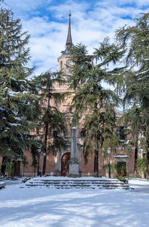 vertical view of bernardas square in the city of alcala de henares after a snowfall with the convent of saint bernard in the background on a sunny day and cloudy blue skyの写真素材