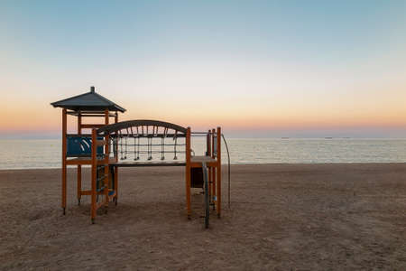 horizontal view of a beach without people at sunset with a playground in the foregroundの写真素材