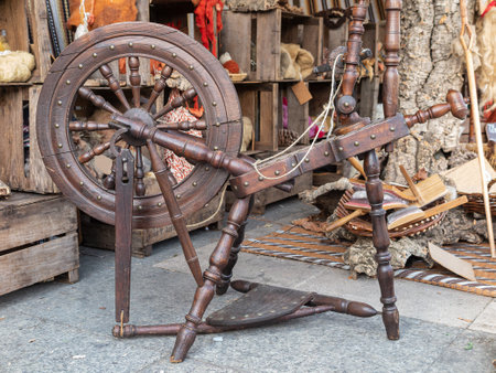 horizontal view of an outdoors shop of wools dyed with natural dyes and an antique pedal wooden spinning wheel in the foregroundの写真素材