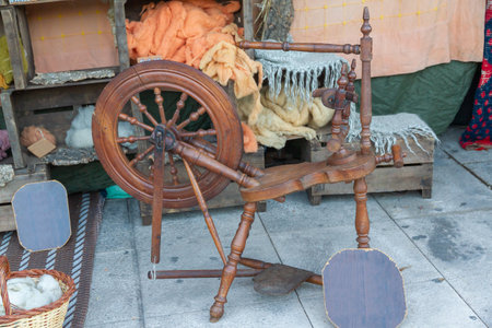 horizontal view of an outdoors shop of wools dyed with natural dyes and an antique pedal wooden spinning wheel in the foregroundの写真素材